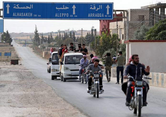 People ride on motorbikes in the border town of Tal Abyad