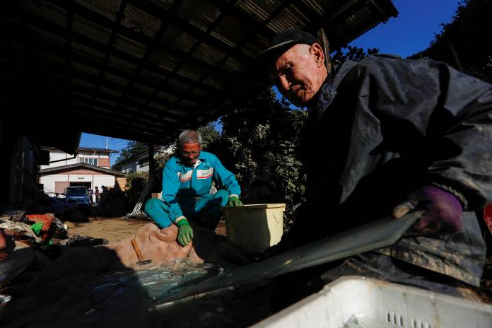 Men crash the glass as they clean debris in the aftermath of Typhoon Hagibis in Yanagawamachi district, Date City