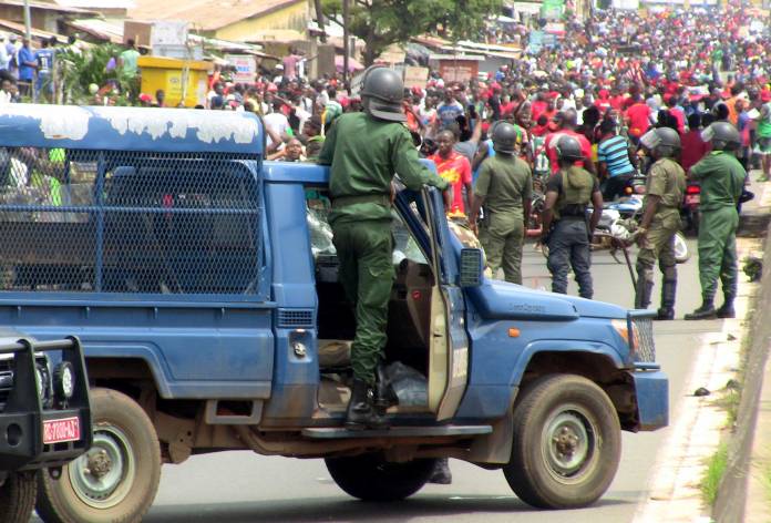 Members of security forces stand guard as people march during a protest over a suspected effort by President Alpha Conde to seek a third term in Conakry