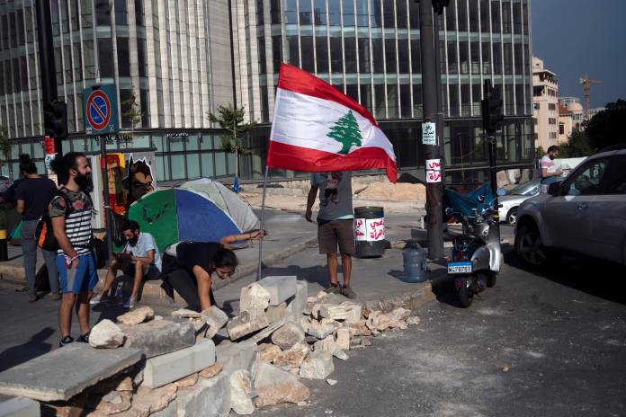 Demonstrators arrange a flag as they block a highway during ongoing anti-government protests in downtown Beirut