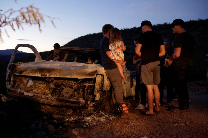 Relatives of slain members of Mexican-American families belonging to Mormon communities observe the burnt wreckage of a vehicle where some of their relatives died, in Bavispe