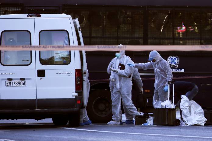 FILE PHOTO: Forensics experts search for evidence outside the French Embassy, where unidentified attackers threw an explosive device which caused a small blast, in Athens