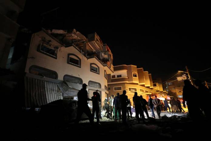 People gather around the home of Palestinian Islamic Jihad field commander Baha Abu Al-Atta after it was hit by an Israeli strike that killed him in Gaza City