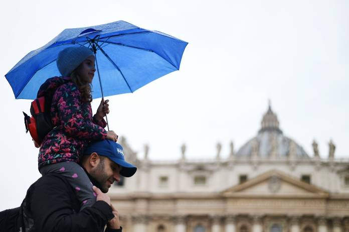 People walk past Saint Peter's Basilica on a rainy day at the Vatican