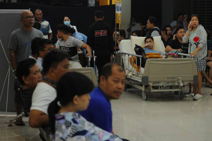Patients and their relatives gather as they are evacuated to the lobby of a hospital following the earthquake in Manado