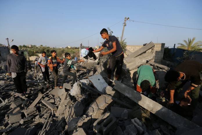 Palestinians collect belongings from a house destroyed in an Israeli air strike in the southern Gaza Strip