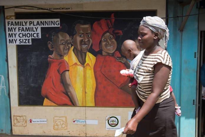 A woman walks past a mural outside a Family Health Options clinic in the Kibera slums in Nairobi, Kenya