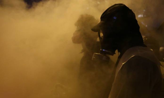 Anti-government protesters stand amid smoke during clashes with police, outside Hong Kong Polytechnic University