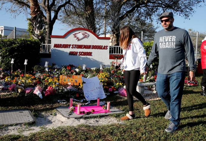 FILE PHOTO: Visitors who asked to not be identified walk past a memorial on the one year anniversary of the shooting which claimed 17 lives at Marjory Stoneman Douglas High School in Parkland