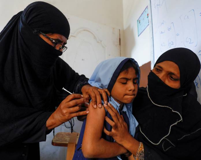 FILE PHOTO: A student reacts as she gets a free anti-typhoid vaccine during the immunisation campaign at a school in Karachi