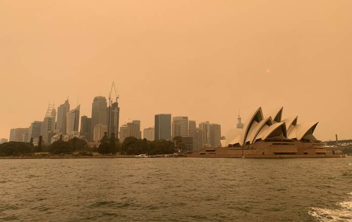 The haze from bushfires obscures the sun setting above the Sydney Opera House in Sydney