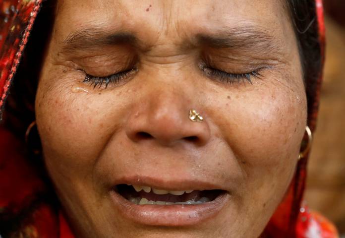A relative of a victim of a fire that swept through a factory where laborers were sleeping, cries outside a hospital mortuary in New Delhi