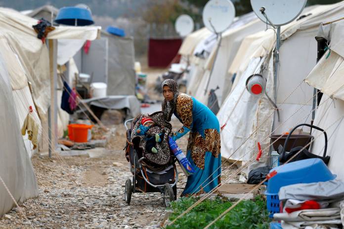 FILE PHOTO: A Syrian refugee mother puts her baby into a stroller in Nizip refugee camp