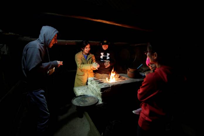 Mariela Ramirez and her family, warm themselves up next to a bonfire at their farm in Jalpan de Serra