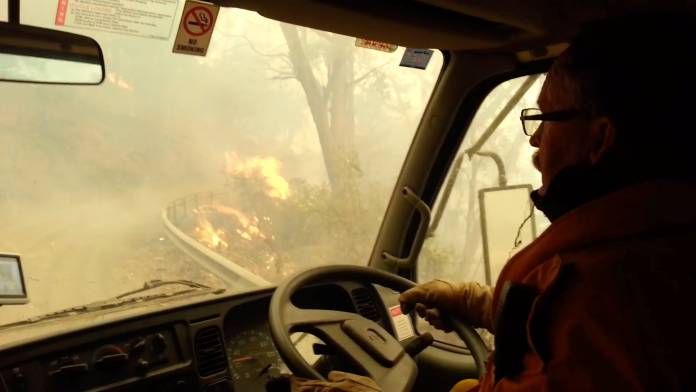 Firefighters drive through flames during evacuation after flames got too large to fight