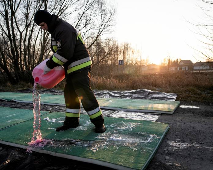 Fireman pours disinfecting liquid on the road in Stary Uscimow, where the bird flu virus was discovered