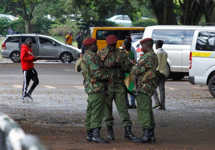Kenya police officers from the General Service Unit (GSU) use their mobile phones during a break from a security patrol at the Uhuru park grounds in Nairobi