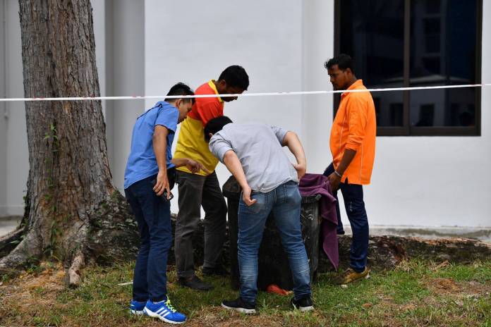 FILE PHOTO: Police officers and cleaners inspect the contents of a bin at a rubbish chute, after a baby was found alive among rubbish in the bin at a public housing estate in Singapore