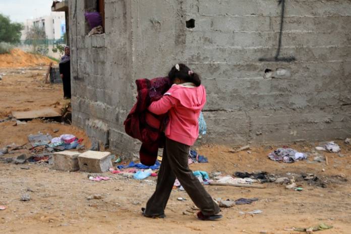 A displaced girl walks near unfinished buildings in Tripoli