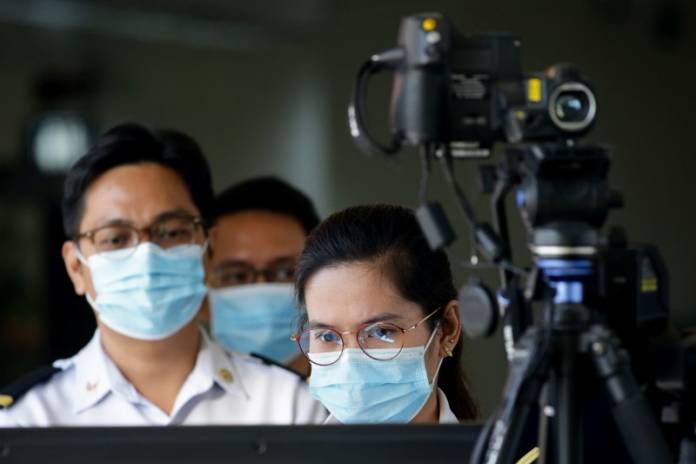 Airport personnel monitor a thermal scanner as passengers arrive at the Ninoy Aquino International Airport in Pasay