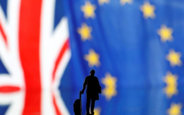 Small toy figure is seen in front of UK and European Union displayed flags in this illustration picture