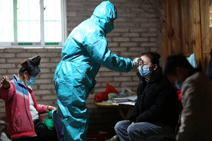 Medical worker in protective suit takes body temperature measurement of a villager as the country is hit by an outbreak of the new coronavirus, in Danzhai
