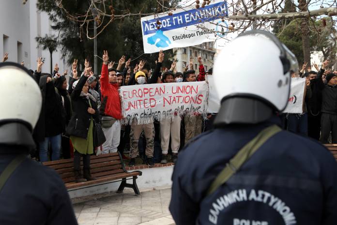 FILE PHOTO: Riot police stand guard as refugees and migrants demonstrate outside the municipal theatre of the city of Mytilene, on the island of Lesbos