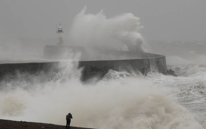 A man photographs large waves caused by Storm Ciara as they hit the the seafront and wall in Newhaven