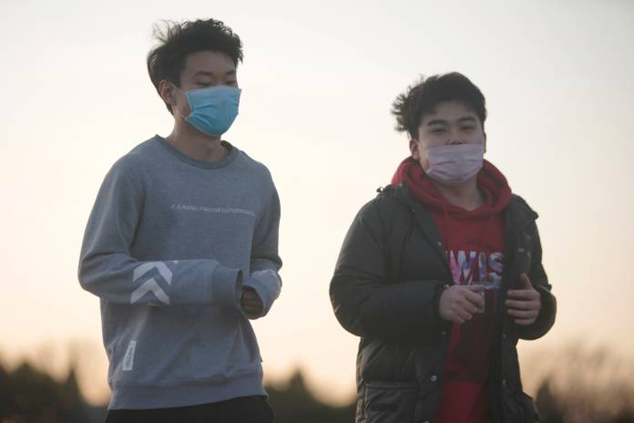 Men wearing face masks jog near the National Centre for the Performing Arts, following an outbreak of the novel coronavirus in the country, in Beijing
