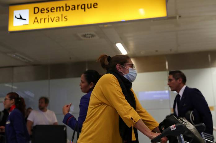 A traveller, wearing a mask as a precautionary measure to avoid contracting coronavirus, arrives on a flight from Europe at Guarulhos International Airport in Guarulhos
