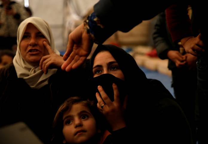 Internally displaced Syrian women and their children sit in a tent in an IDP camp located near Idlib