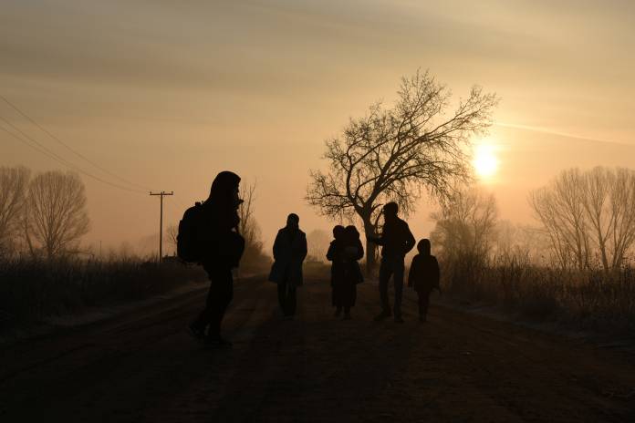 Migrants walk on a dirt road at dawn, after crossing from Turkey into Greece, near the town of Orestiada