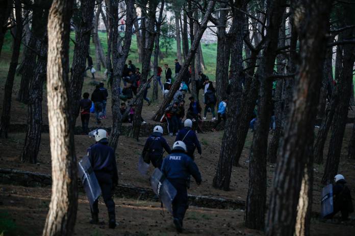 Riot police officers try to disperse a group of migrants gathered outside the port of Mytilene