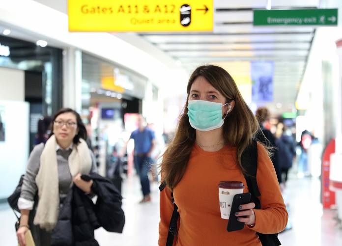 A woman wears a surgical mask as she walks through Terminal 5 at Heathrow Airport in London A woman wears a surgical mask as she walks through Terminal 5 at Heathrow Airport in London