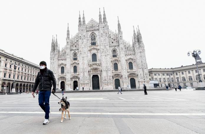 A man wearing a protective face mask walks a dog in Duomo square after a decree orders for the whole of Italy to be on lockdown in an unprecedented clampdown aimed at beating the coronavirus, in Milan A man wearing a protective face mask walks a dog in Duomo square after a decree orders for the whole of Italy to be on lockdown in an unprecedented clampdown aimed at beating the coronavirus, in Milan