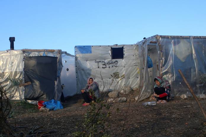 FILE PHOTO: Women sit next to tents, at a makeshift camp for refugees and migrants next to the Moria camp, on the island of Lesbos FILE PHOTO: Women sit next to tents, at a makeshift camp for refugees and migrants next to the Moria camp, on the island of Lesbos