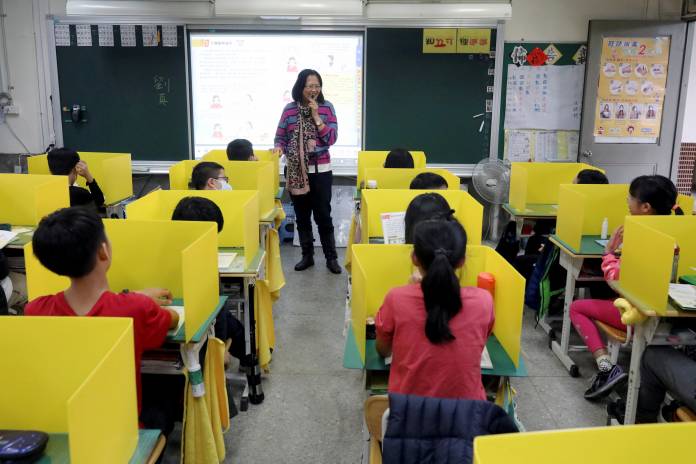Pupils sit in desks with yellow dividers at Dajia Elementary school in Taipei Pupils sit in desks with yellow dividers at Dajia Elementary school in Taipei