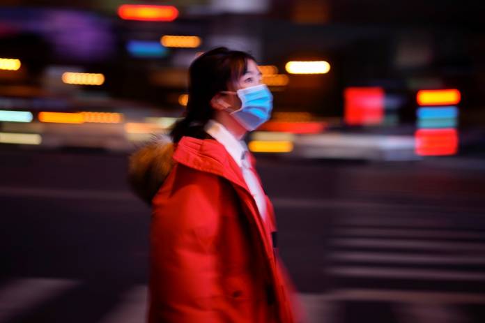 A woman wearing a protective face mask is seen on a crossroad following the outbreak of coronavirus disease (COVID-19), in downtown Shanghai A woman wearing a protective face mask is seen on a crossroad following the outbreak of coronavirus disease (COVID-19), in downtown Shanghai