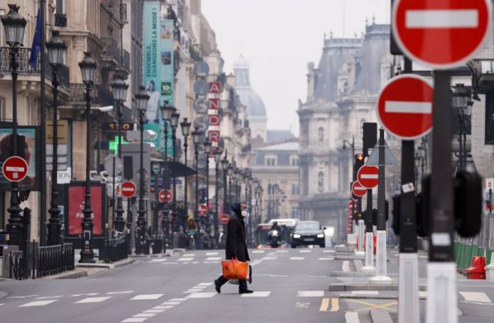 A man wearing a protective face mask crosses the deserted Rue de Rivoli in Paris A man wearing a protective face mask crosses the deserted Rue de Rivoli in Paris