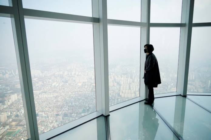 A woman wearing a mask to prevent contracting the coronavirus looks at a view of central Seoul A woman wearing a mask to prevent contracting the coronavirus looks at a view of central Seoul