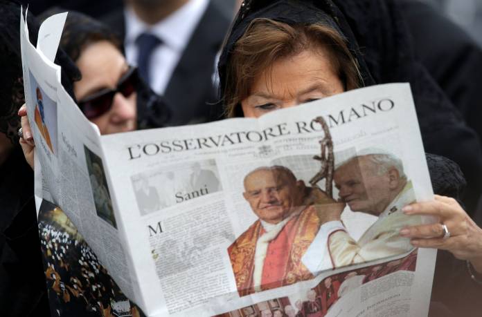 FILE PHOTO: A woman reads a copy of the Vatican newspaper L'Osservatore Romano as she waits for the canonisation ceremony in St Peter's Square at the Vatican FILE PHOTO: A woman reads a copy of the Vatican newspaper L'Osservatore Romano as she waits for the canonisation ceremony in St Peter's Square at the Vatican