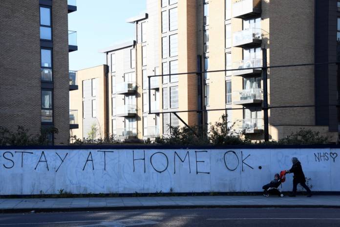 A woman walks past graffiti on a wall in Brentford, as the spread of the coronavirus disease (COVID-19) continues, London, Britain, April 1, 2020. REUTERS/Toby Melville