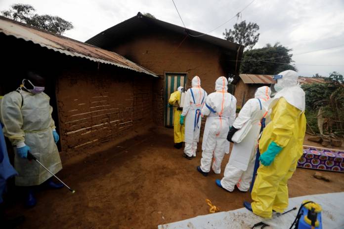 FILE PHOTO: Kavota Mugisha Robert (L), a healthcare worker who volunteered in the Ebola response, stands with decontamination gear as his colleague prepare to enter a house where a woman, 85, is suspected of dying of Ebola in the Eastern Congolese town of Beni in the Democratic Republic of Congo, October 8, 2019. REUTERS/Zohra Bensemra/File Photo