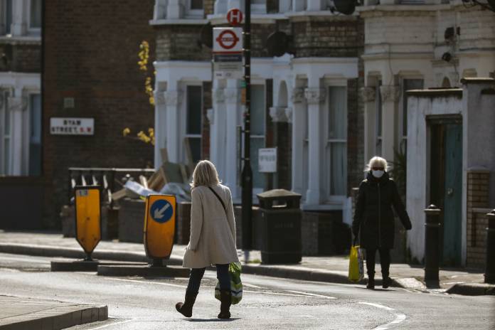 Women with shopping bags walk on a deserted residential street in London