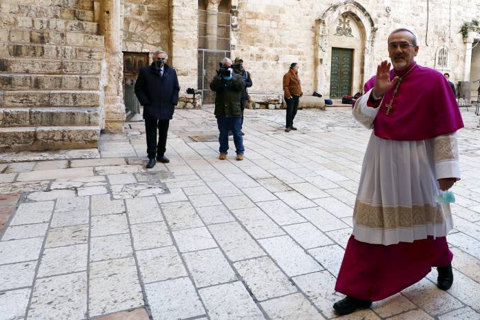Archbishop Pierbattista Pizzaballa, waves as he enters the Church of the Holy Sepulchre before the start of the Easter Sunday service amid the coronavirus disease (COVID-19) outbreak, in Jerusalem's Old City