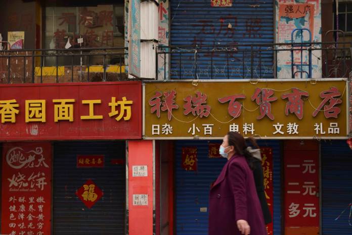 Women wearing face masks walk past closed shops in Suifenhe
