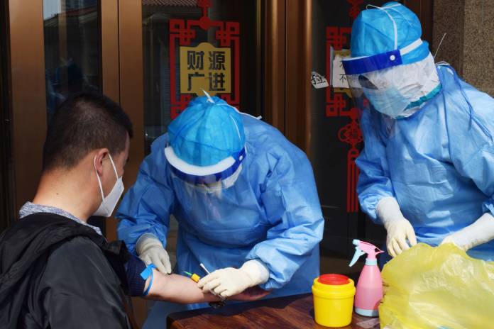 Worker draws blood from a man to conduct a test for antibodies against the coronavirus disease (COVID-19) in Suifenhe