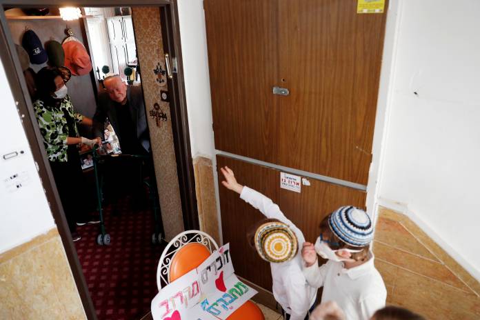 Neria and Netanel, great-grandsons of Elias Feinzilberg, a 102-year-old Holocaust survivor, stand by the door of his home in Jerusalem as Israel marks Holocaust Remembrance Day under coronavirus disease (COVID-19) restrictions