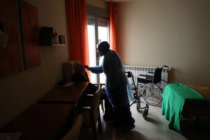 A worker in a protective gear cares for a resident during lockdown amid the coronavirus disease (COVID-19) outbreak at Oteruelo nursing home in Valverde del Majano