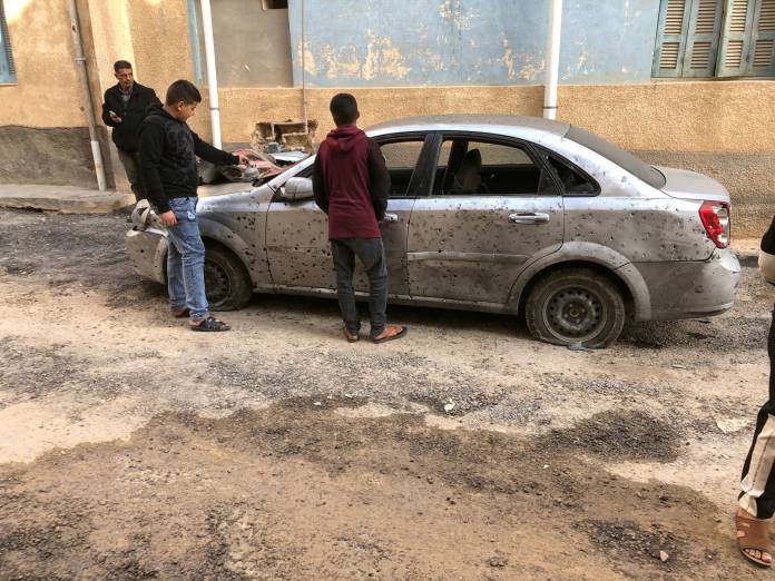 FILE PHOTO: Libyan boys check a damaged car after a shell fell on a residential area at Hadba al-Badri district, in Tripoli